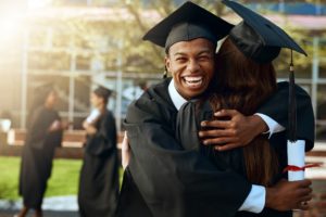 Assessment in Higher Education - Two college graduates hugging in their caps and gowns